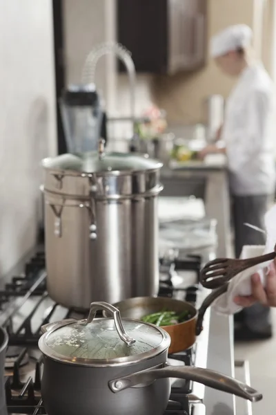 Chef heating saucepan on stove — Stock Photo, Image