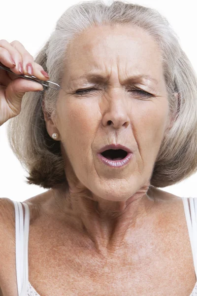 Senior woman tweezing eyebrows — Stock Photo, Image