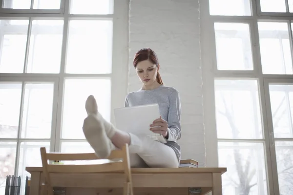 Femme assise sur le bureau avec ordinateur portable — Photo