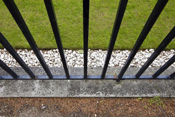 Ijzeren hek, gras en steentjes — Stockfoto