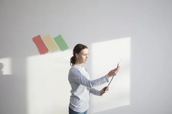 Mujer decidiendo sobre la muestra de pintura en el nuevo apartamento —  Fotos de Stock