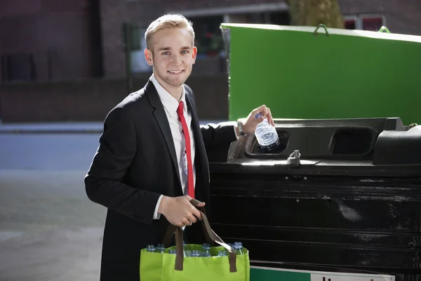 Geschäftsmann wirft Plastikflaschen in Mülleimer — Stockfoto