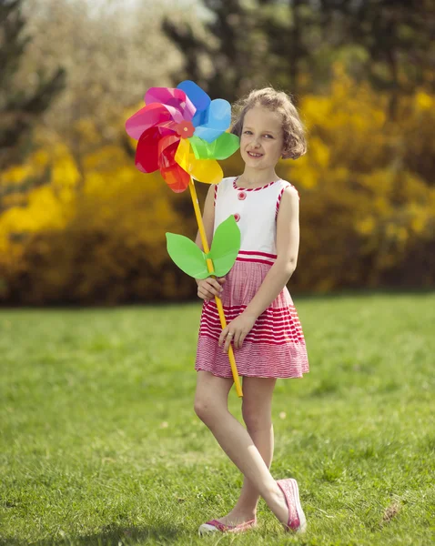 Niña sosteniendo rueda de viento flor — Foto de Stock