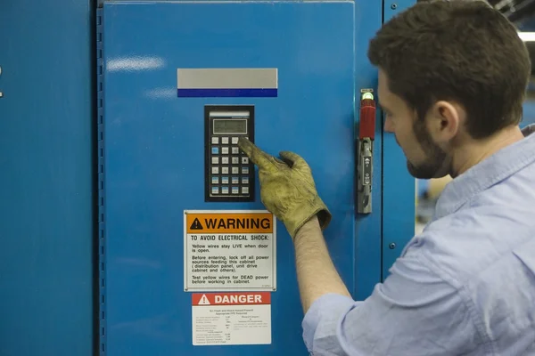 Man pressing keypad in newspaper factory — Stock Photo, Image