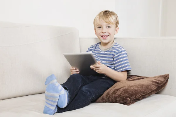 Niño sosteniendo la tableta PC en el sofá —  Fotos de Stock