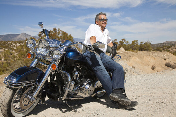 Senior man leaning on motorcycle