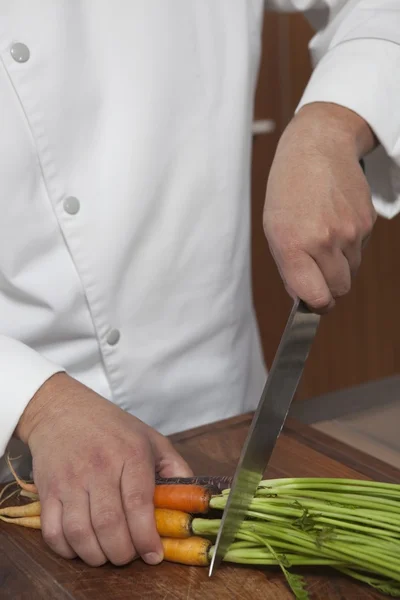 Chef cutting carrots at kitchen — Stock Photo, Image