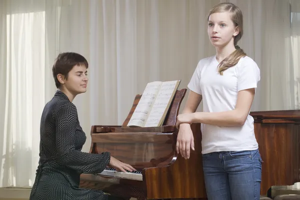 Girl singing accompanied by teacher — Stock Photo, Image