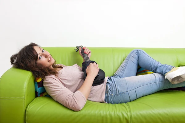 Žena na gauči hraje na ukulele — Stock fotografie