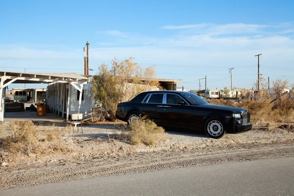 Rolls Royce aparcado en un lado de la carretera cerca de casas abandonadas — Foto de Stock