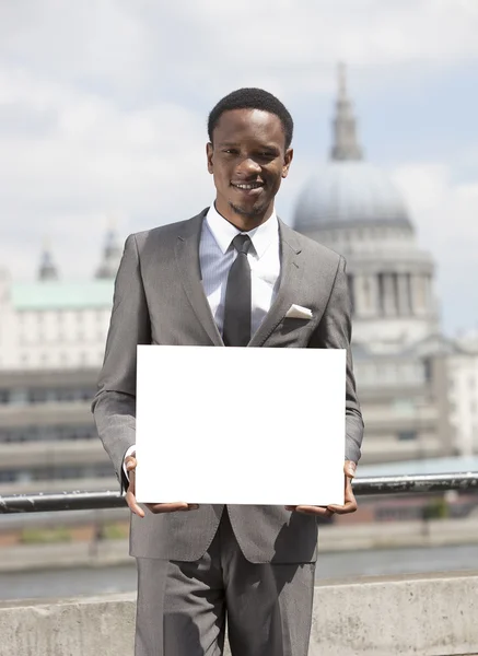 Hombre de negocios afroamericano sosteniendo cartón en blanco — Foto de Stock