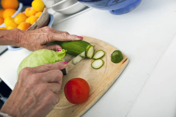 Mujer mayor cortando verduras — Foto de Stock