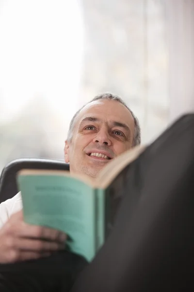 Mittlerer erwachsener Mann entspannt zu Hause beim Lesen eines Buches — Stockfoto