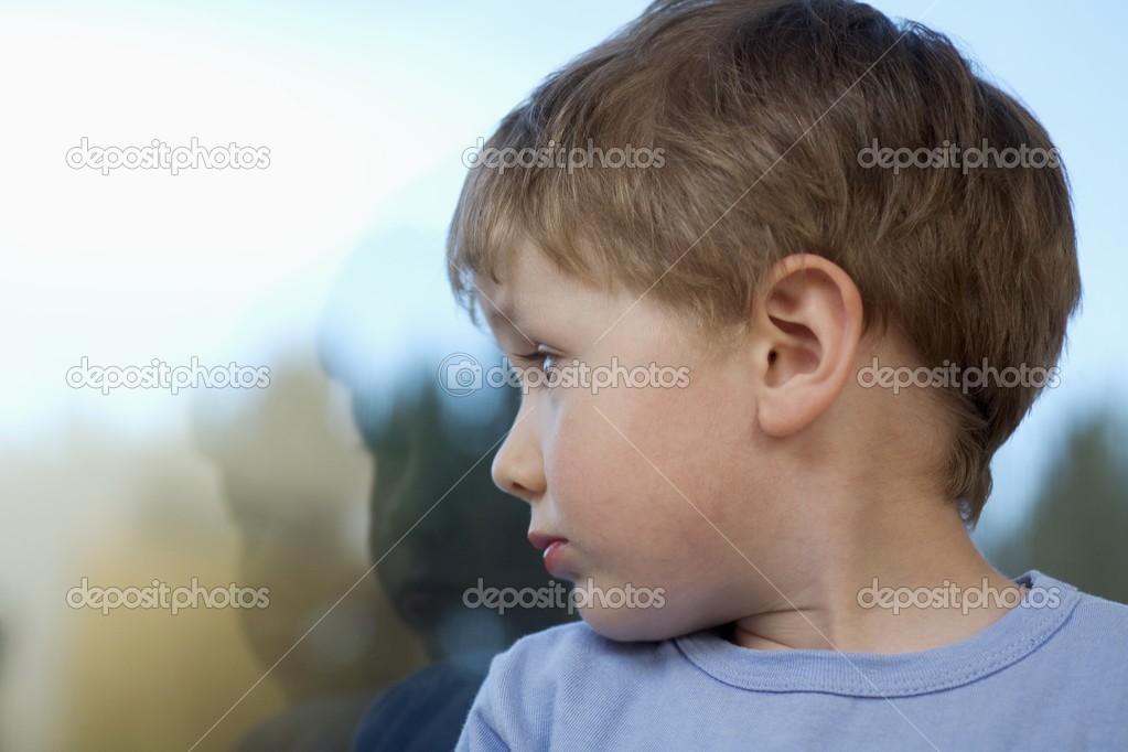 Young boy looking back at shadow in glass