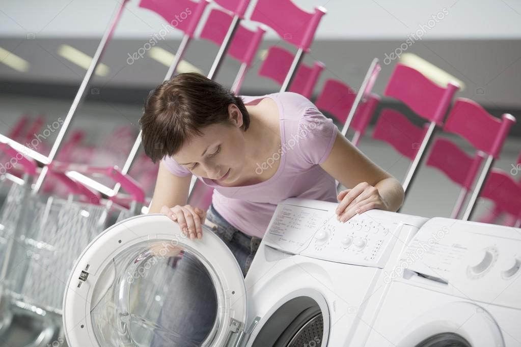 Young woman chooses washing machine in shopping mall