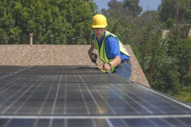 Maintenance worker measures solar array on rooftop clipart