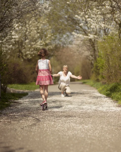 Girl riding scooter to mother — Stock Photo, Image