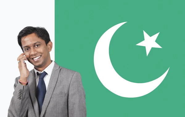 Empresário usando telefone sobre bandeira paquistanesa — Fotografia de Stock