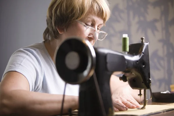 Mature woman works at sewing machine — Stock Photo, Image