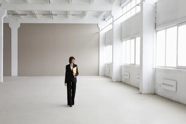 Business woman stands in empty warehouse — Stock Photo, Image