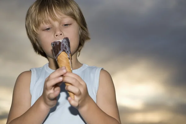 Мальчик в жилете держит растопленное шоколадное мороженое — стоковое фото