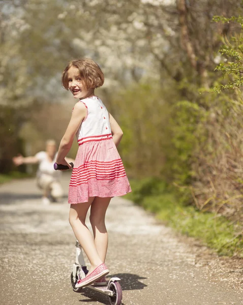 Meisje paardrijden scooter aan moeder — Stockfoto