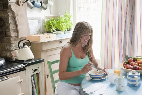 Mujer embarazada sentada en la mesa de la cocina desayunando — Foto de Stock