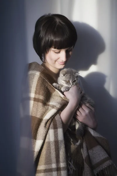 Woman in blanket stands holding kitten — Stock Photo, Image