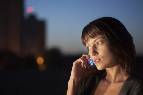 Woman talks on mobile phone at night