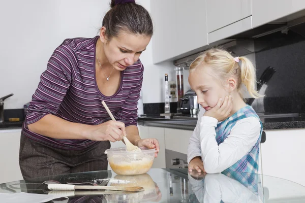 Mädchen schaut Mutter beim Kochen in Küche an — Stockfoto