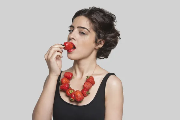 Seductive young woman eats strawberry necklace — Stock Photo, Image