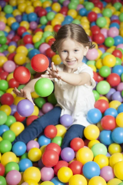 Menina no poço de bola jogando bolas — Fotografia de Stock