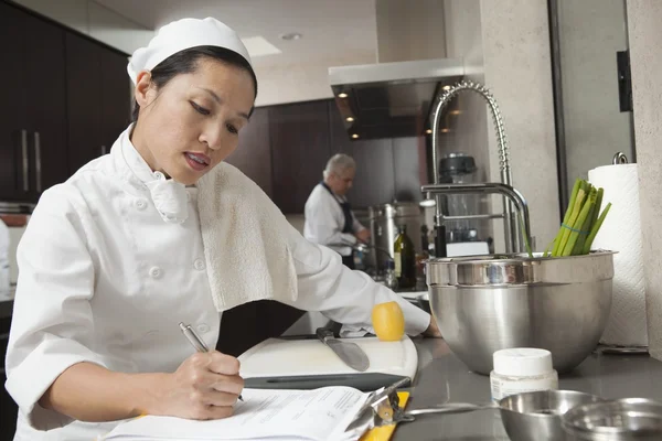 Vrouw chef-kok schrijven op Klembord — Stockfoto