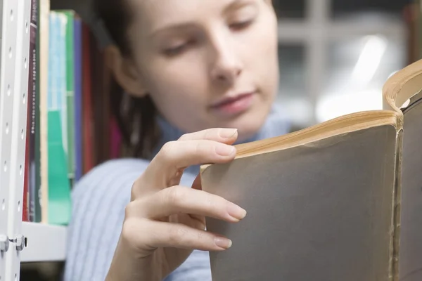 Junge Frau liest Buch in Bibliothek — Stockfoto