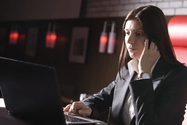 Mujer de negocios usando portátil y teléfono móvil —  Fotos de Stock