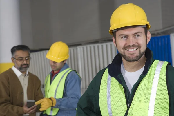 Man standing in factory with colleagues — Stock Photo, Image