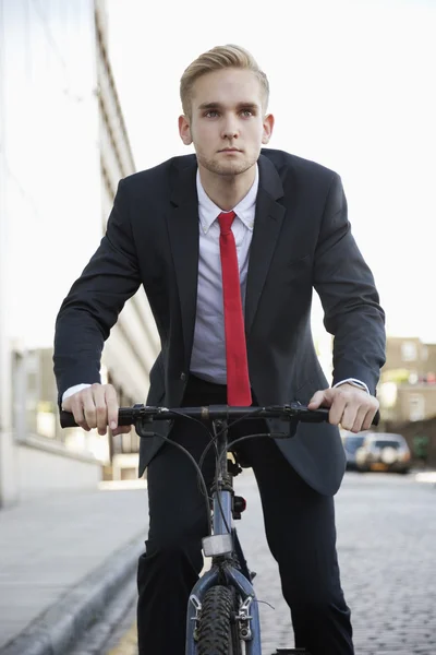 Businessman riding bicycle on street — Stock Photo, Image