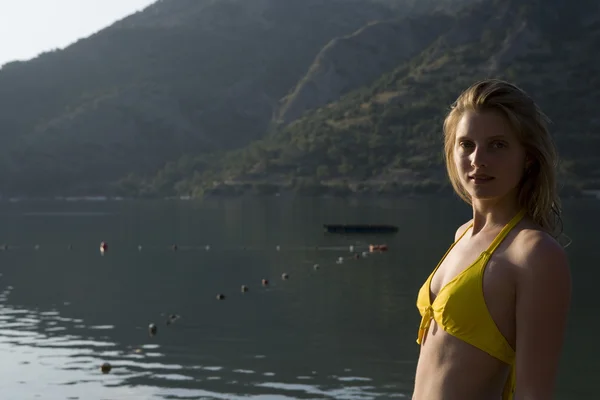 Bikinili sarışın kadın geri kamera Gölü'nün sabah güneş ışığı altında görünüyor. — Stok fotoğraf