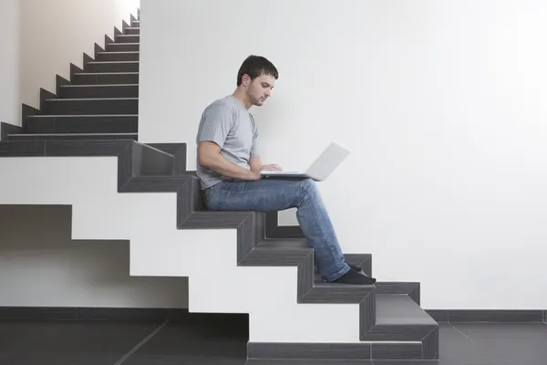 Man sits on staircase with laptop — Stock Photo, Image