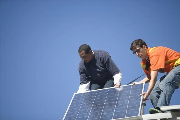 Hommes soulevant un grand panneau solaire — Photo