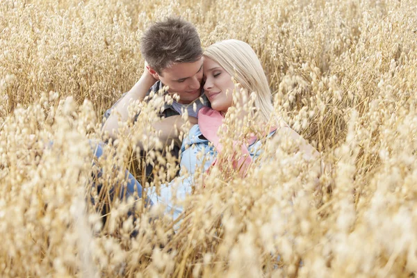 Pareja relajándose en medio del campo — Foto de Stock