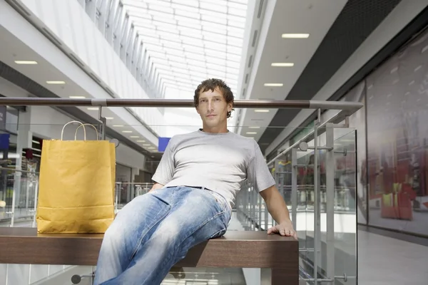 Young man sits in new shopping centre — Stock Photo, Image