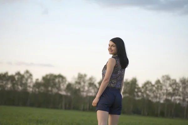 Jonge vrouw in korte broek wandelingen naar bos — Stockfoto