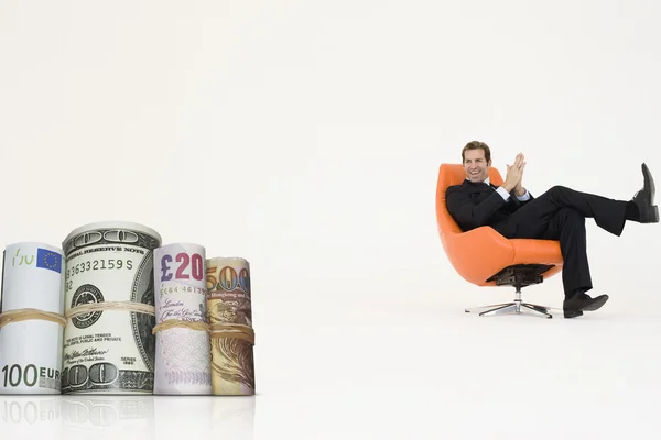 Happy businessman looking at money rolls — Stock Photo, Image