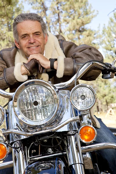 Senior man leaning on motorcycle handlebars — Stock Photo, Image