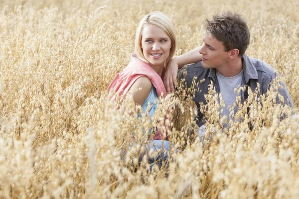 Woman sitting with boyfriend amidst field — Stock Photo, Image