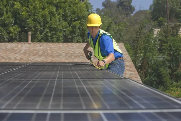 Maintenance worker measures solar array on rooftop — Stock Photo, Image