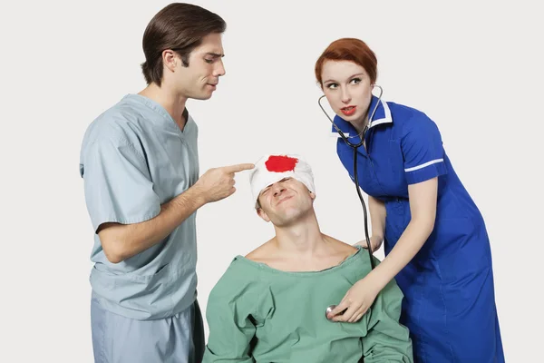 Doctor with nurse examining patient — Stock Photo, Image