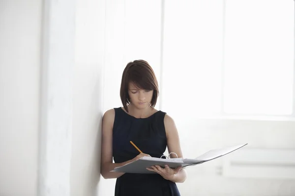 Business woman on writes in file in empty warehouse — Stock Photo, Image