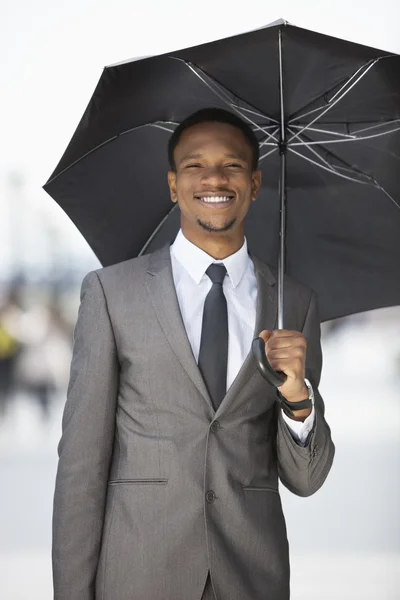 Africano empresário americano segurando guarda-chuva — Fotografia de Stock